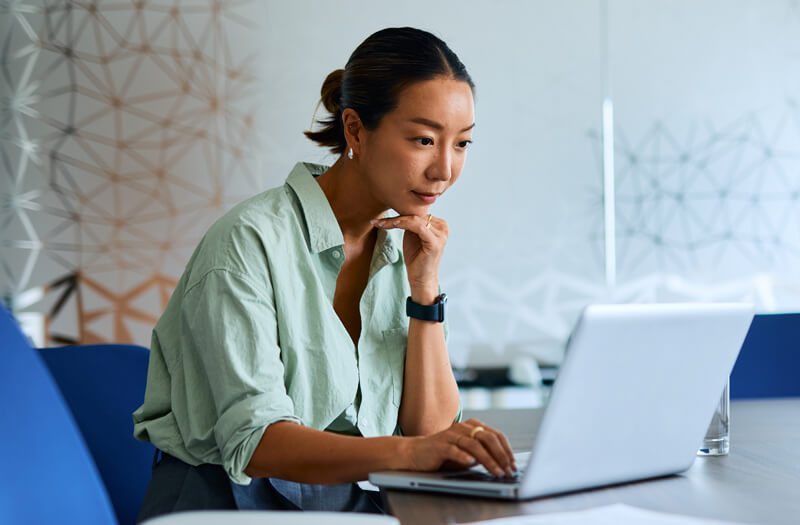 Professional businesswoman working on a laptop in a modern office, exploring OpenAI solutions to boost productivity.