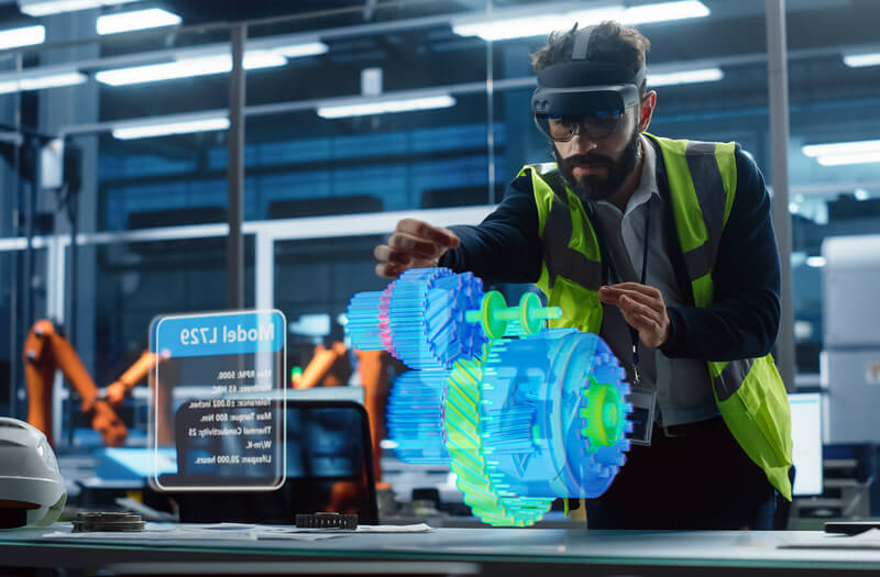 Engineer reviewing technical plans on a tablet computer while seated at a worktable in a modern workspace. Engineer Using Tablet at Workspace