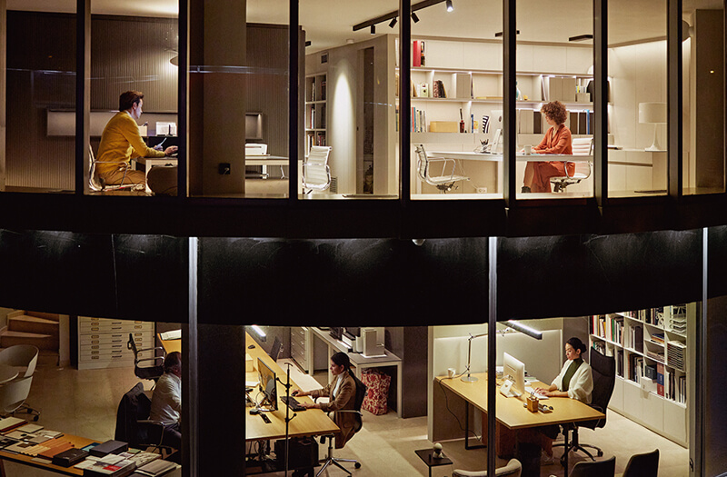 Power essential IT and AI applications with Insight and APC by Schneider Electric Two-story view of a modern office with workers at dusk.