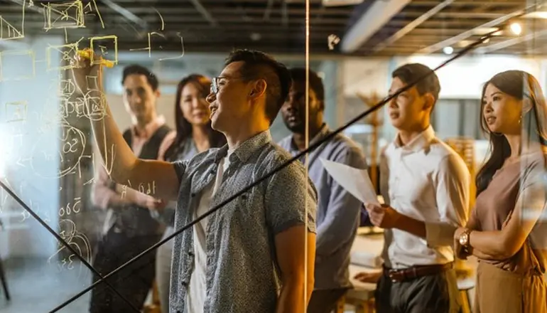 People in a meeting drawing on a board.