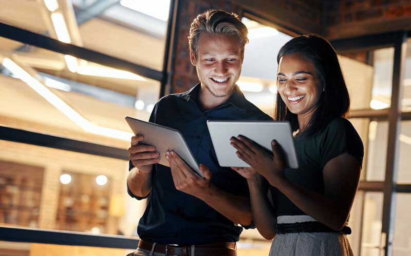 Two users smiling looking at tablet devices