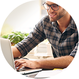 Smiling man in plaid uses laptop computer