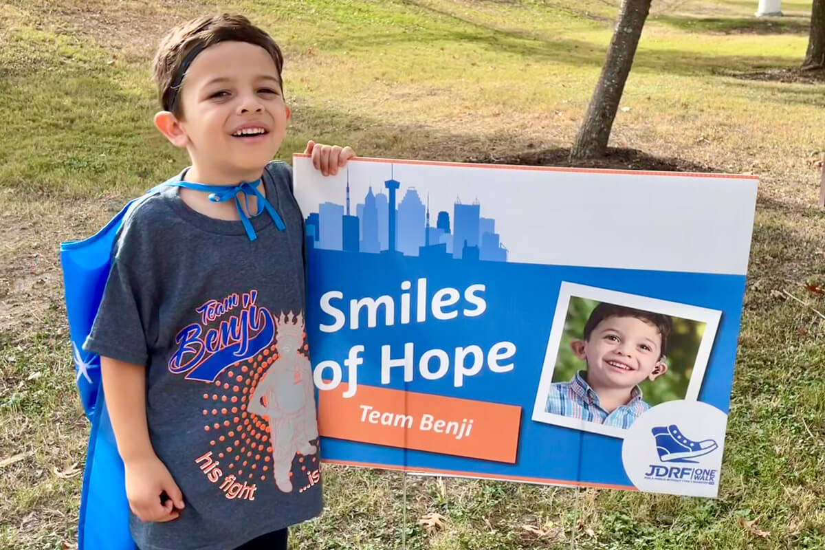 Benji stands in front of a Smiles for Hope sign