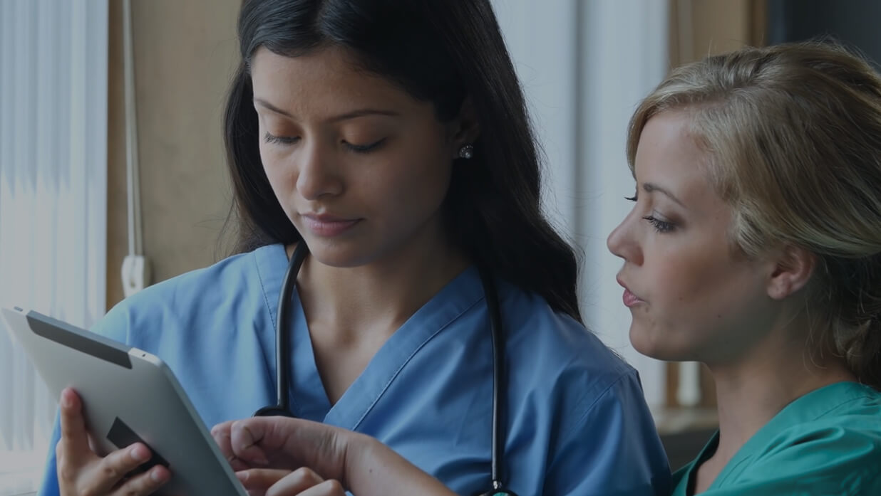 Two nurses discuss data on tablet
