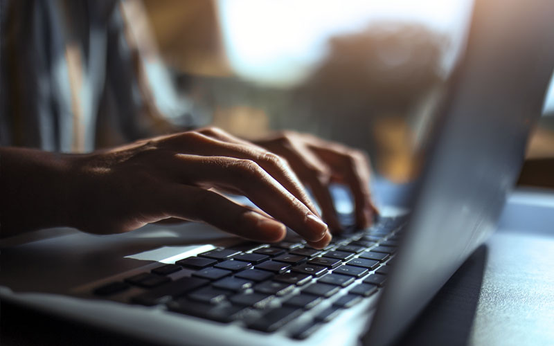 Close up of hands typing on a laptop keyboard