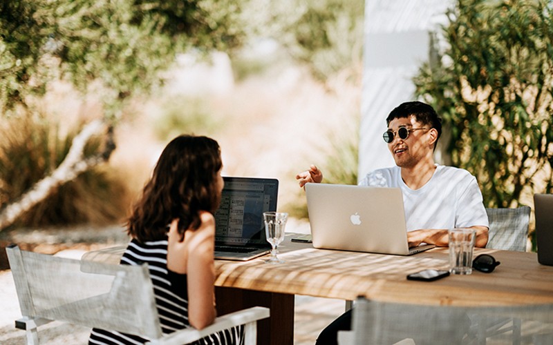 Two people working outside on laptops