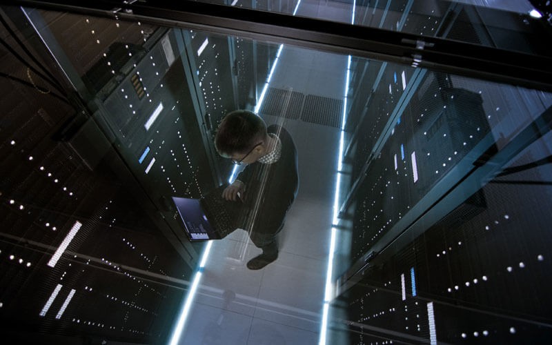 Man in a server room holding laptop