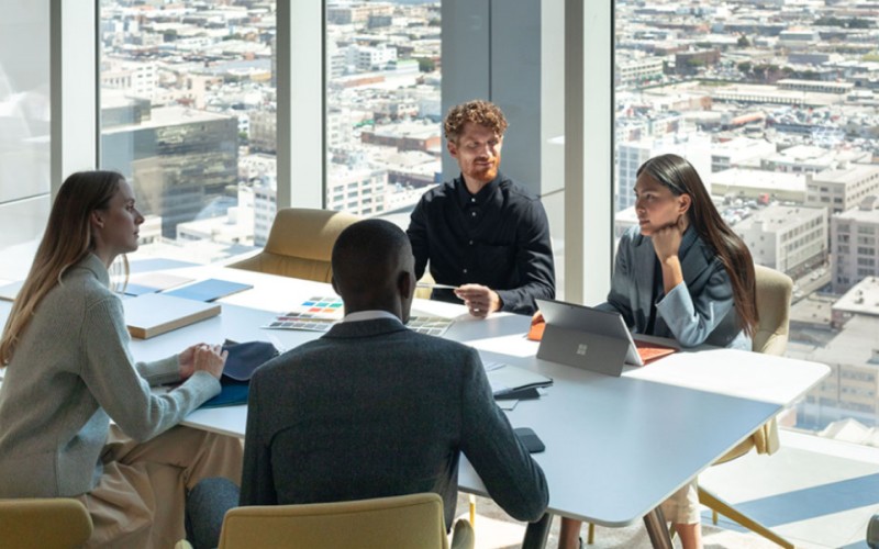 Four people working at table with devices