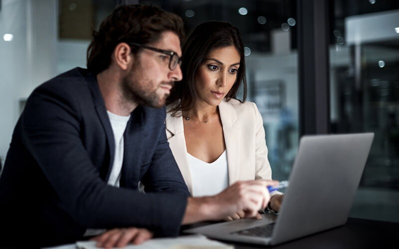 Two people discussing and infront of a laptop