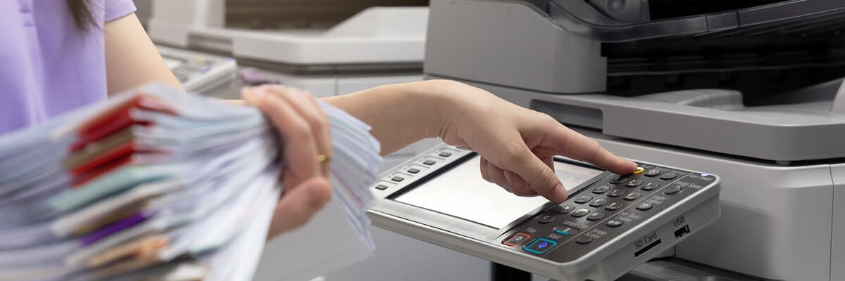 Ensure your printing and imaging environment is protected. Healthcare professional holding a stack of patient records while using a Multi-function printer. MFP printers, HP Printers