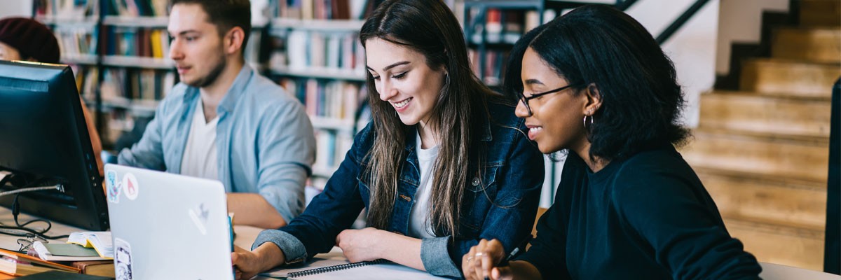 Close up of college students collaborating in computer lab library area