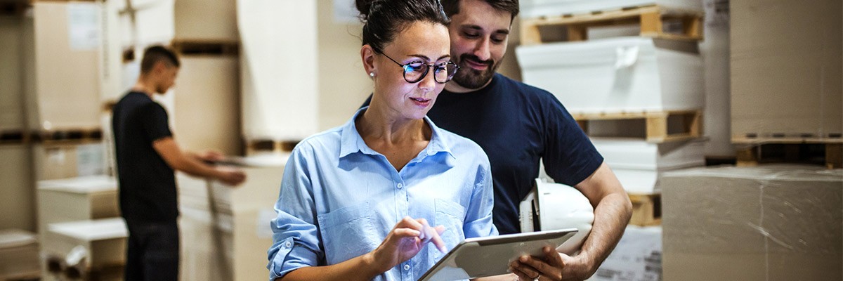 Two employees using tablet in warehouse