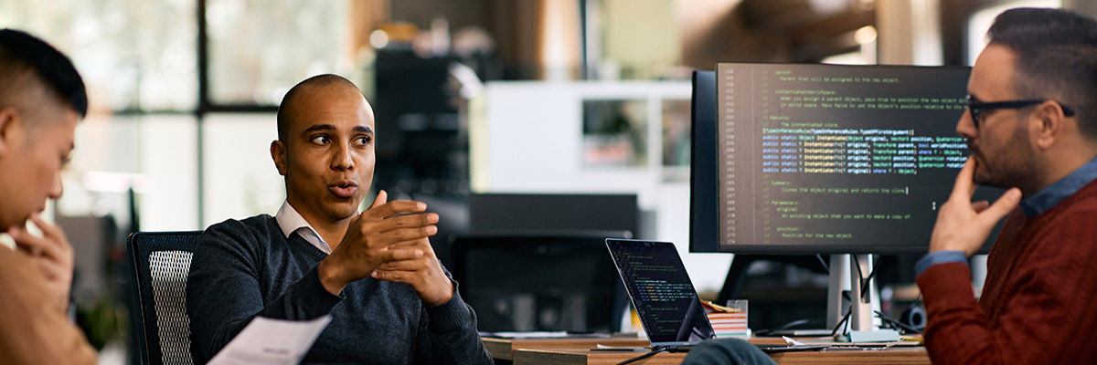 Developers discussing around work desks