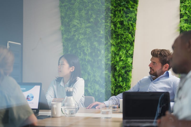 Business professionals gathered in meeting room on devices