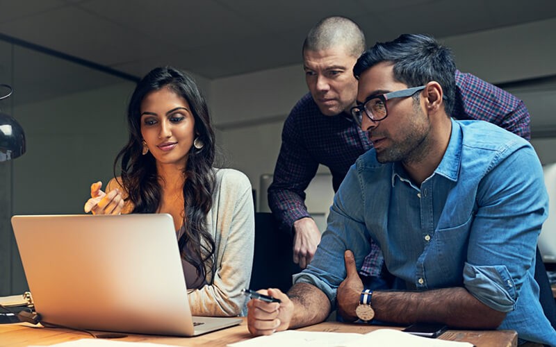 Group of business professionals discussing report on computer