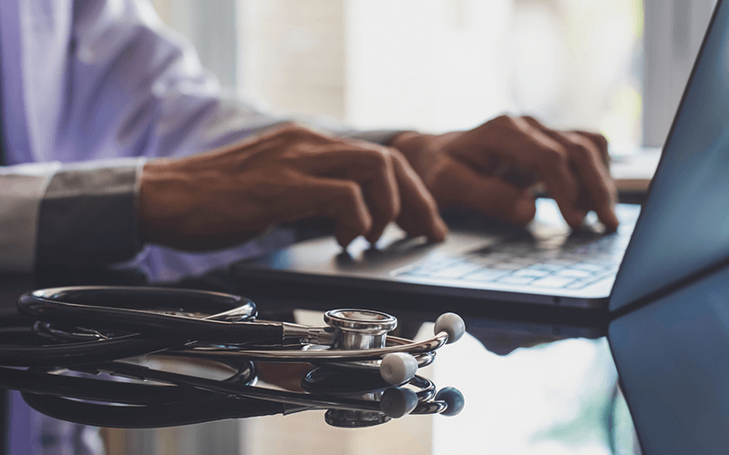 Doctor on laptop computer with stethoscope nearby 