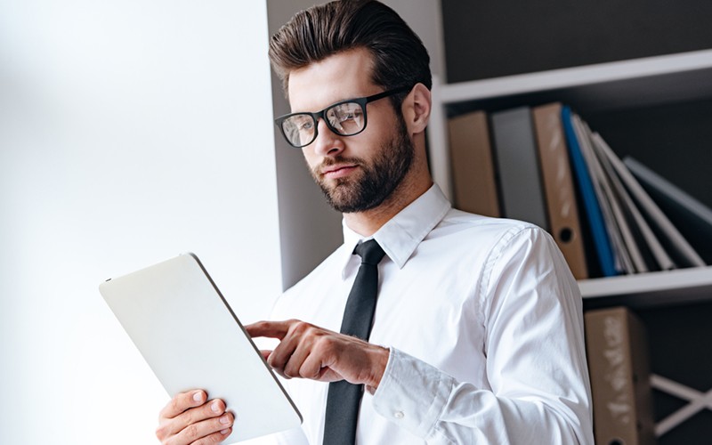 Professional businessman reading report off of tablet device utilizing the cloud