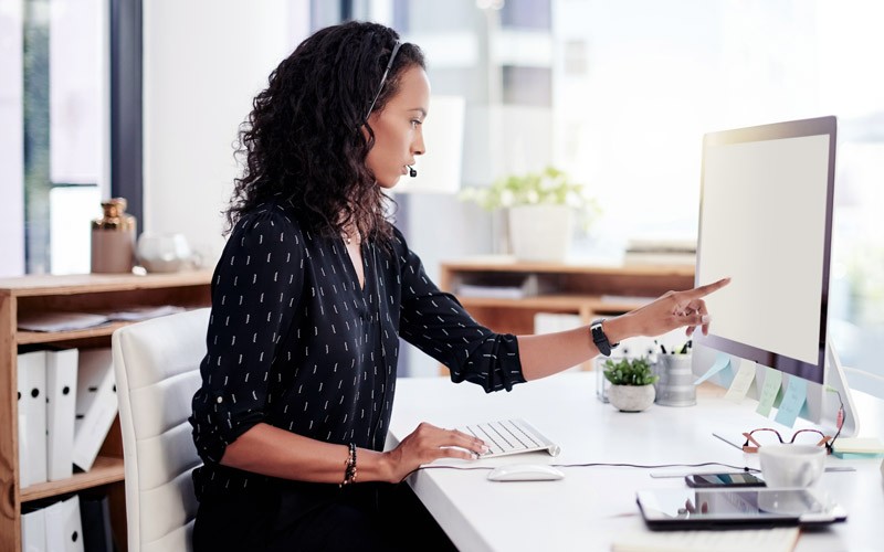 Businesswoman on headset working on desktop computer