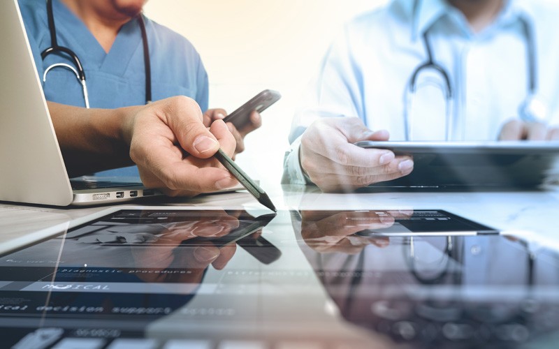 Two doctors discuss patient results over tablets