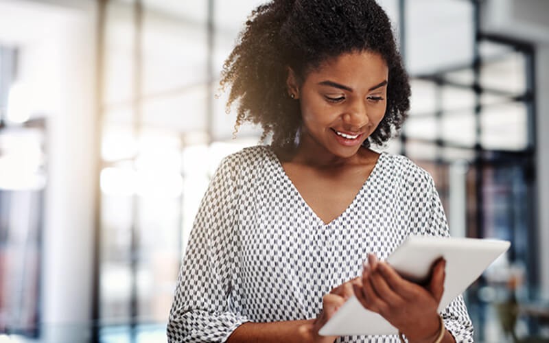 Smiling businesswoman on tablet device in open office