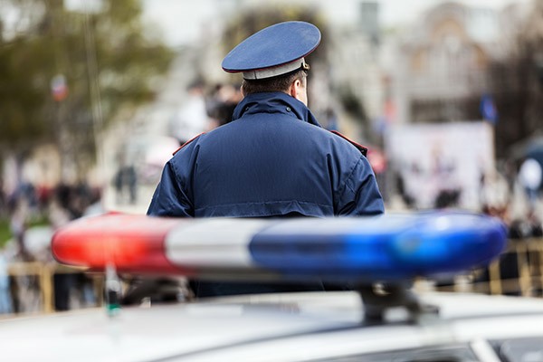 Police officer in crowd standing next to police car