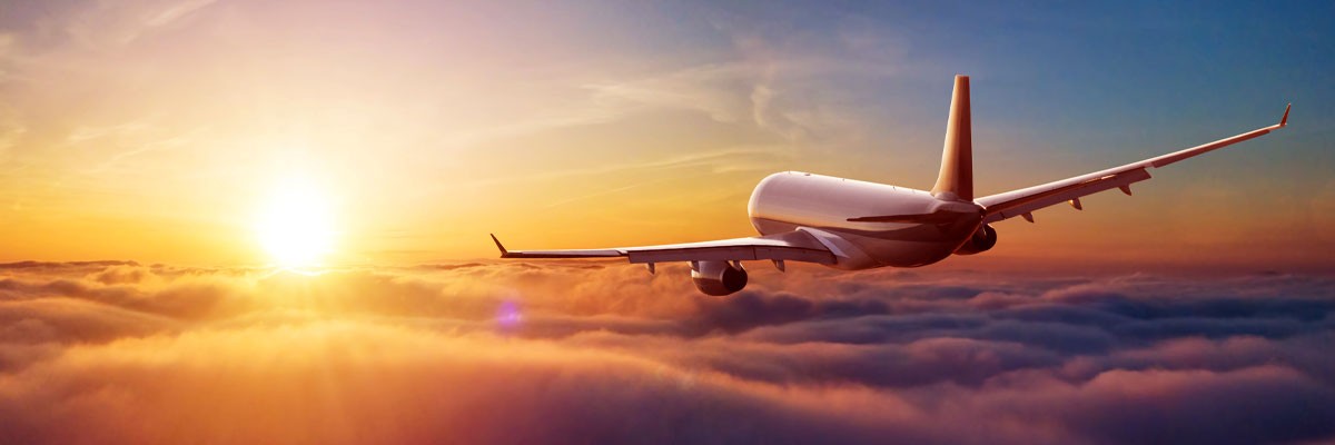 Airplane flying above clouds during sunset