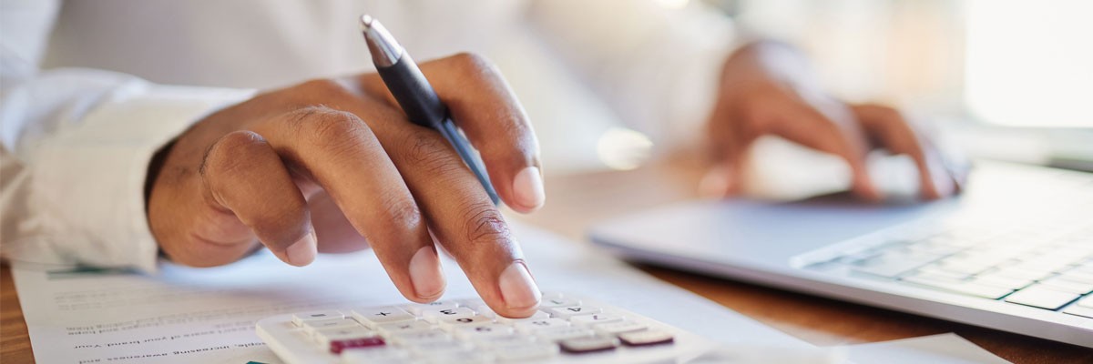 Close up of hands typing on laptop computer and calculator