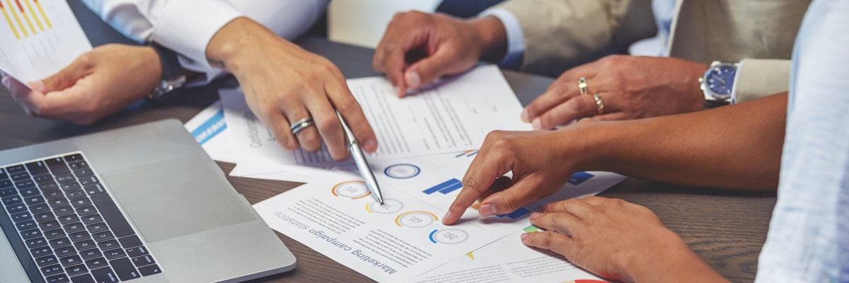 Group of financial analysts gathering around to review data