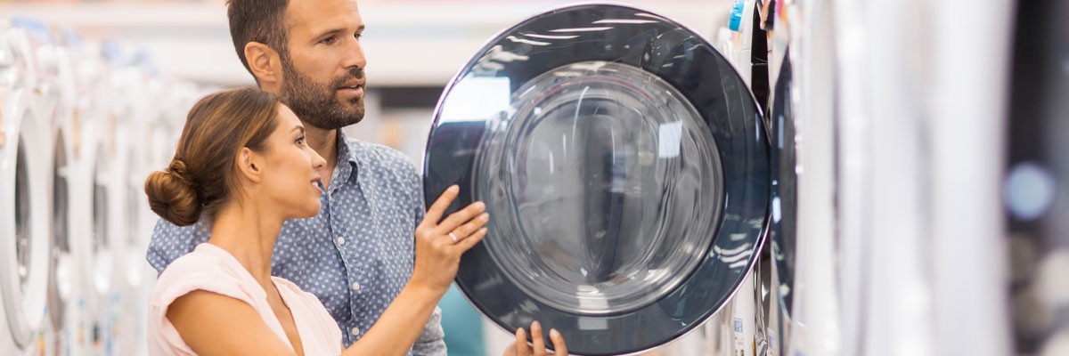 Two people in appliance store looking at washers and dryers