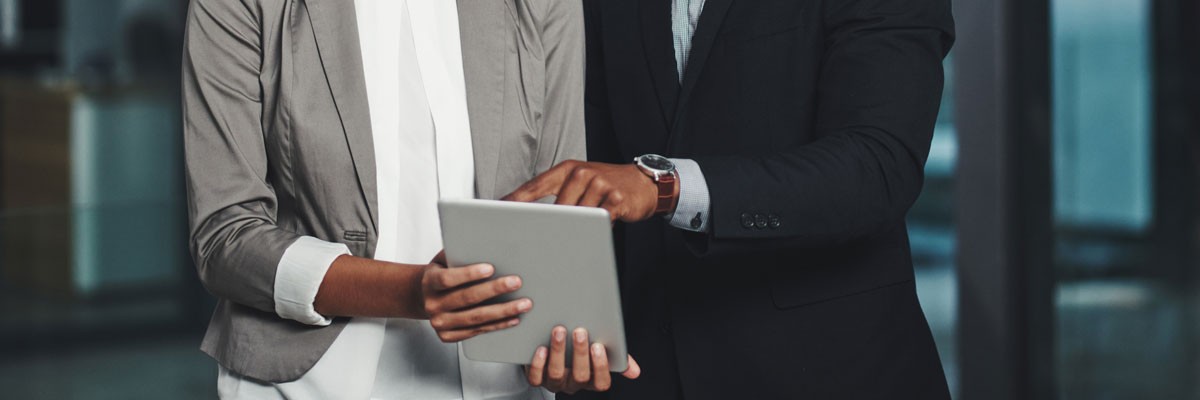 Two financial analysts review data on tablet device