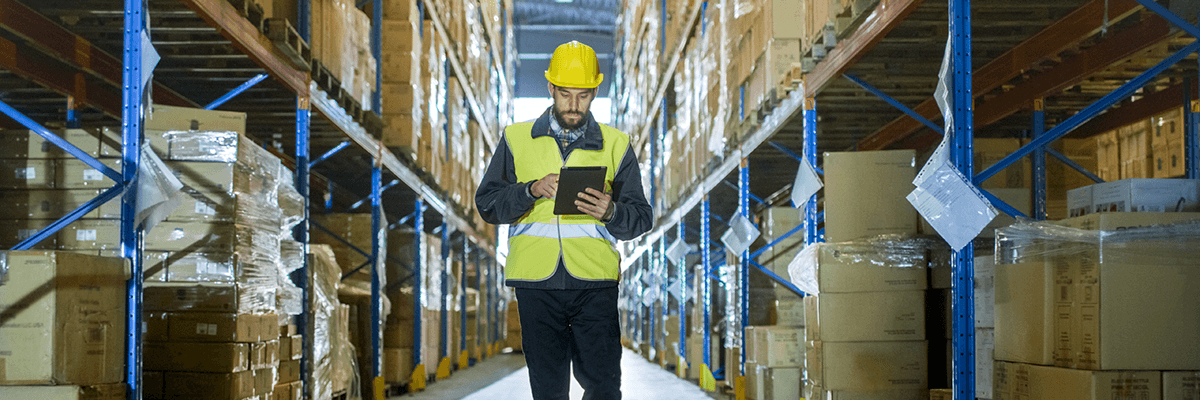 Retailer Builds Distribution Center Equipped for the Future Man with tablet works in distribution center warehouse