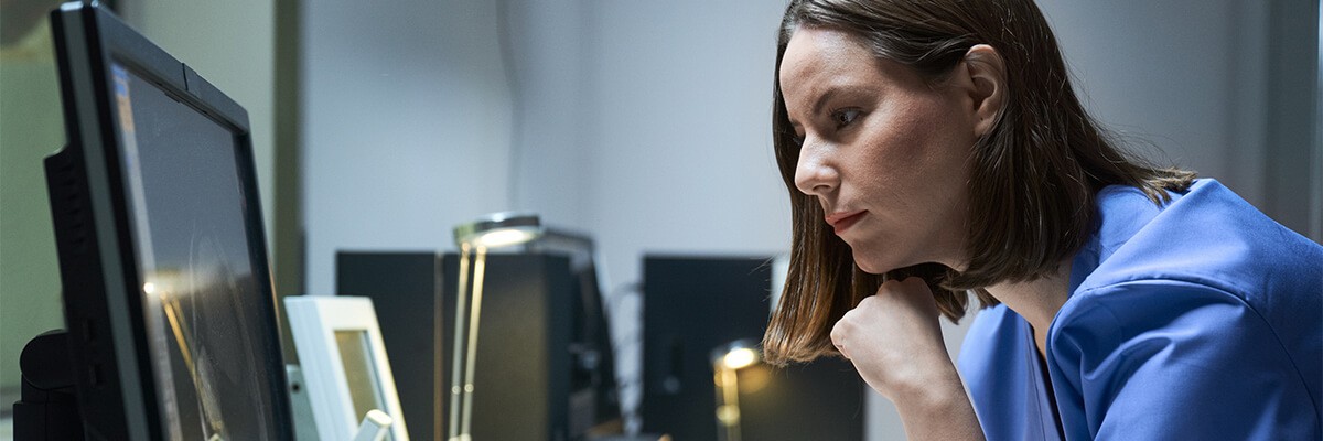 Female urgent care employee at desk securely reviewing patient data