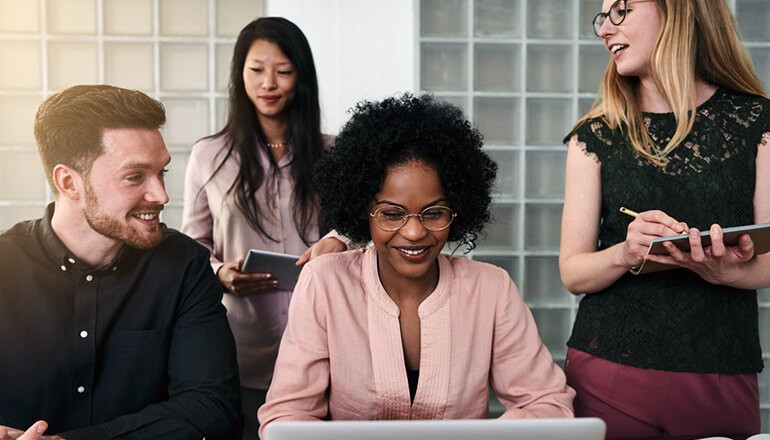 Business colleagues gathered around laptop computer using devices
