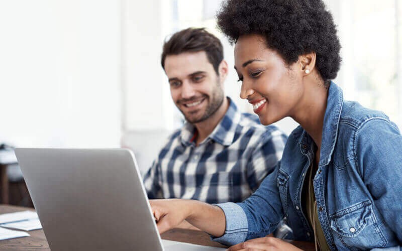 Smiling business woman talking to man on laptop in office
