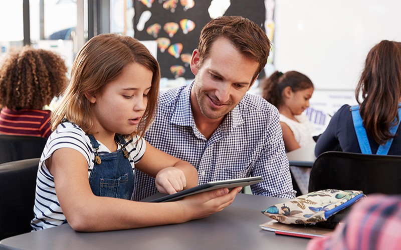 Teacher helping student with tablet device