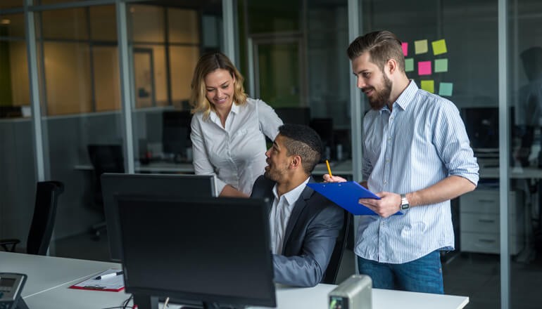 Three business employees collaborating in front of desktop