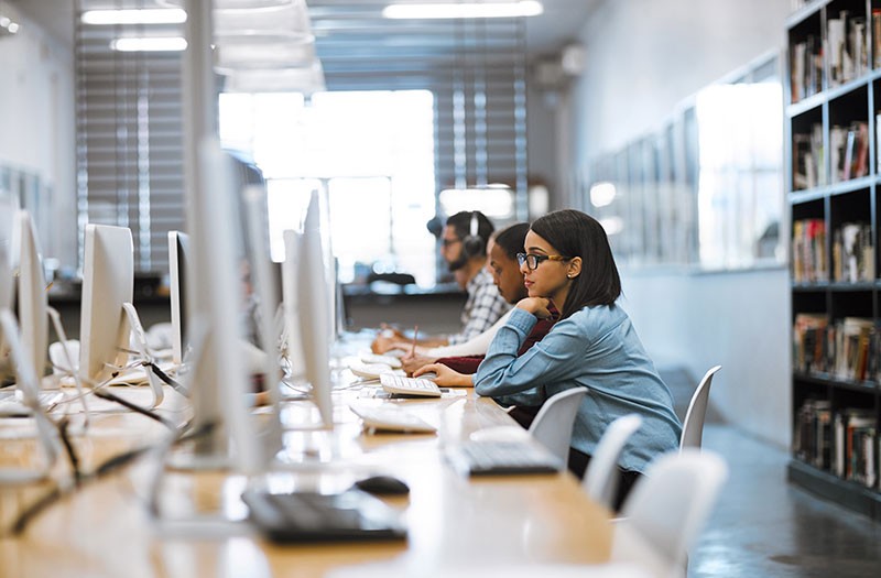 College students work in open computer lab library area