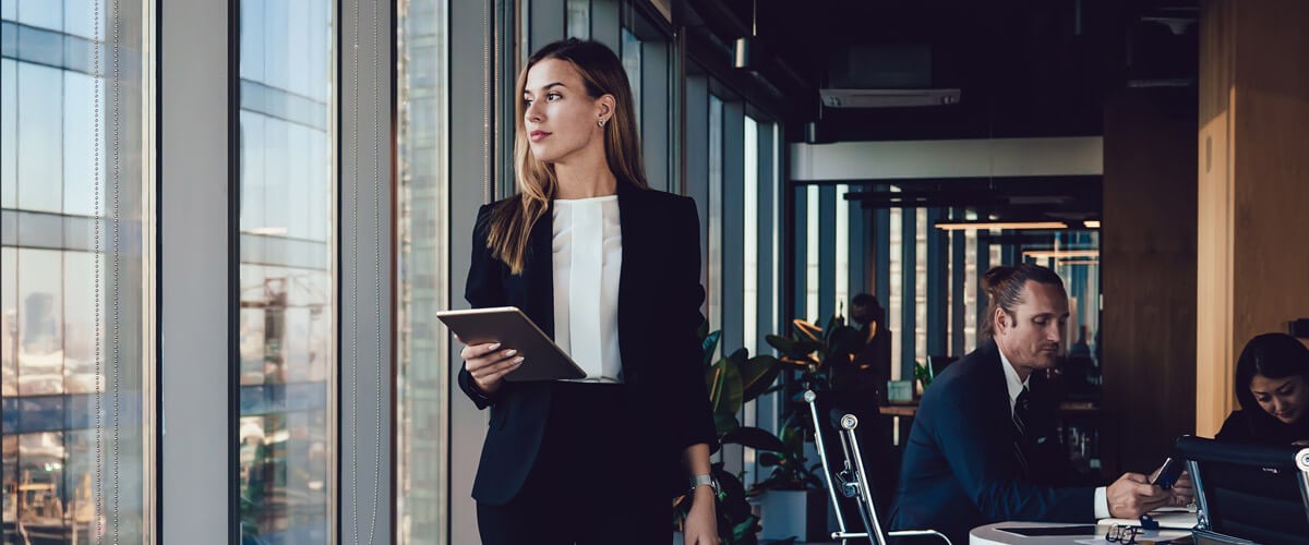 Business professional walking in modern office and looking out window.