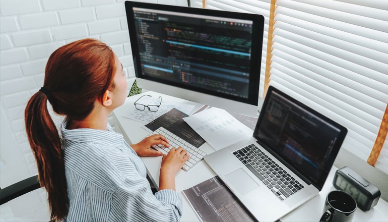 Female developer works at desk with multiple monitors 
