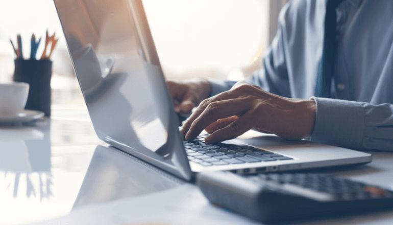 Utilize Federal Funding to achieve all your network goals Businessman typing on laptop keyboard with calculator nearby