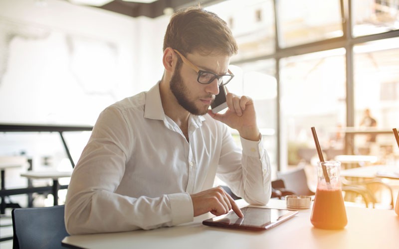 Business man speaking on mobile phone while using tablet device