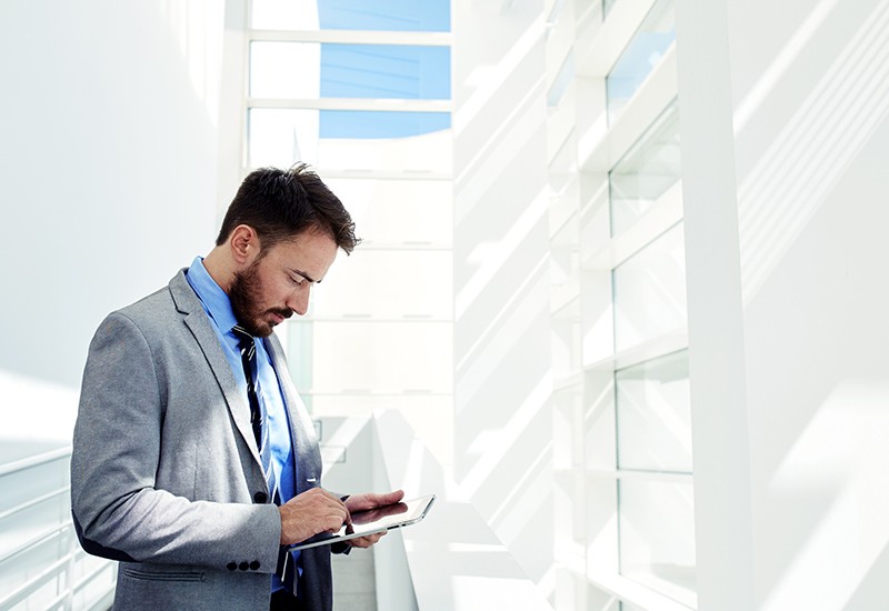 Businessman on iPad in sun lit hallway