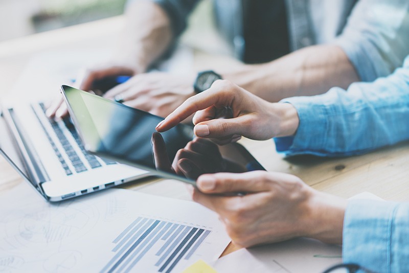 Business professionals using multiple mobile devices during meeting