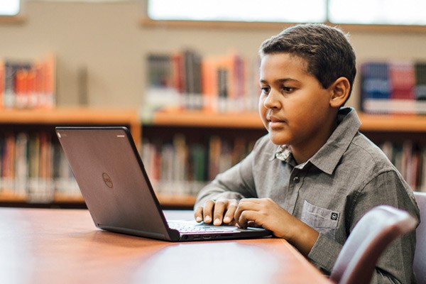 Dell mobile computing solutions for education Student doing homework at desk in library on a Dell Chromebook netbook