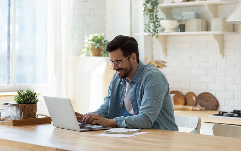 Business man holding mobile device in front of laptop