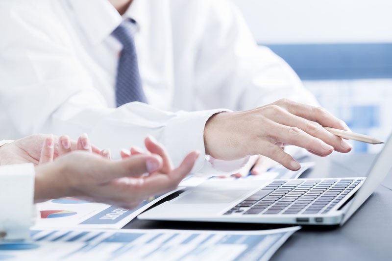 Closeup of two sets of business men's hands working on laptop.
