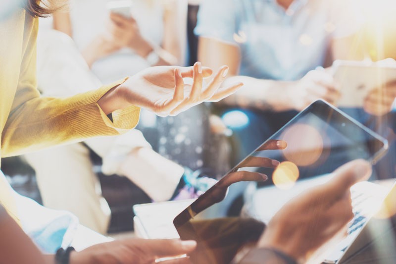 Closeup of a group of office workers having a meeting using tablets.