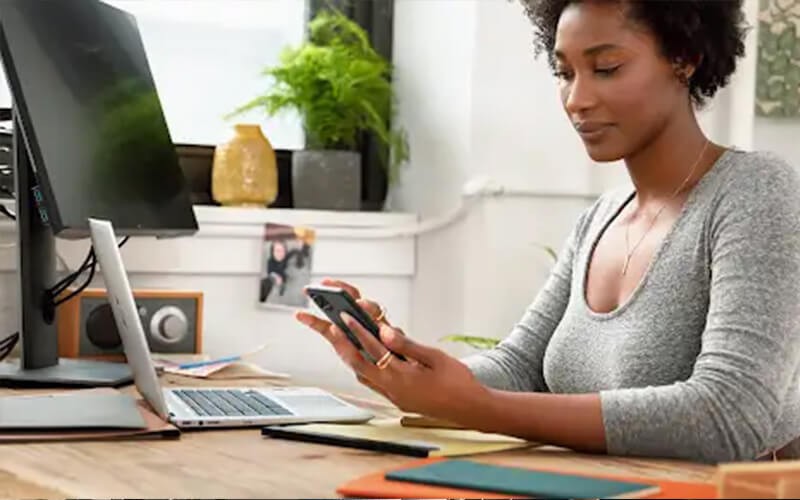 Woman using her phone in front of laptop