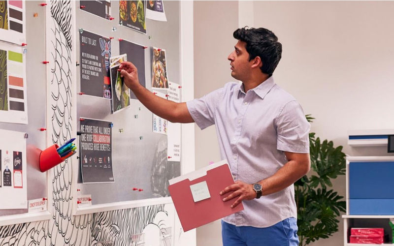 man tacking paper to a board in an office