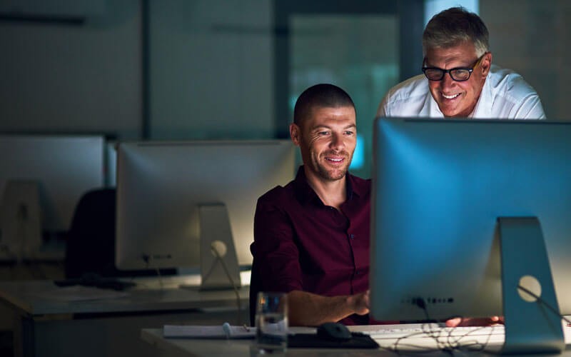 Two men working together on computer